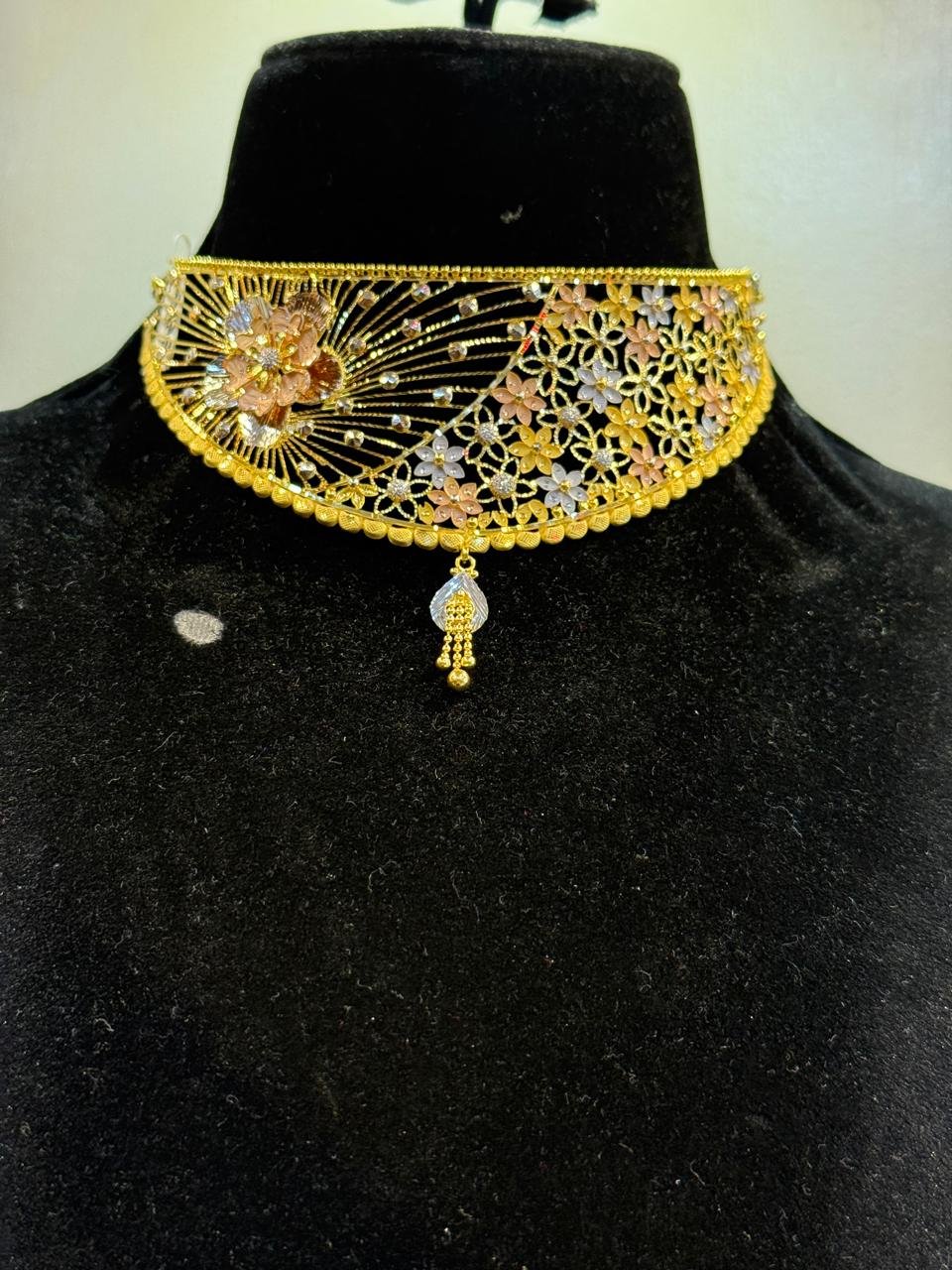 A gold choker with a leaf and floral cluster centrepiece