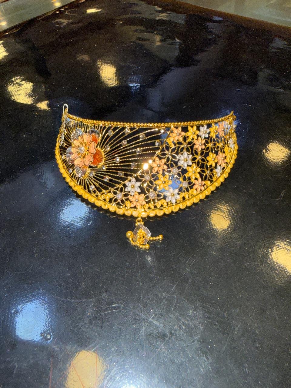 A gold choker with rose-gold floral and leaf detailing