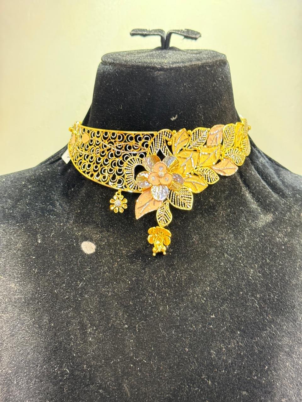 A gold choker with a tri-tone floral centre and teardrop fringe