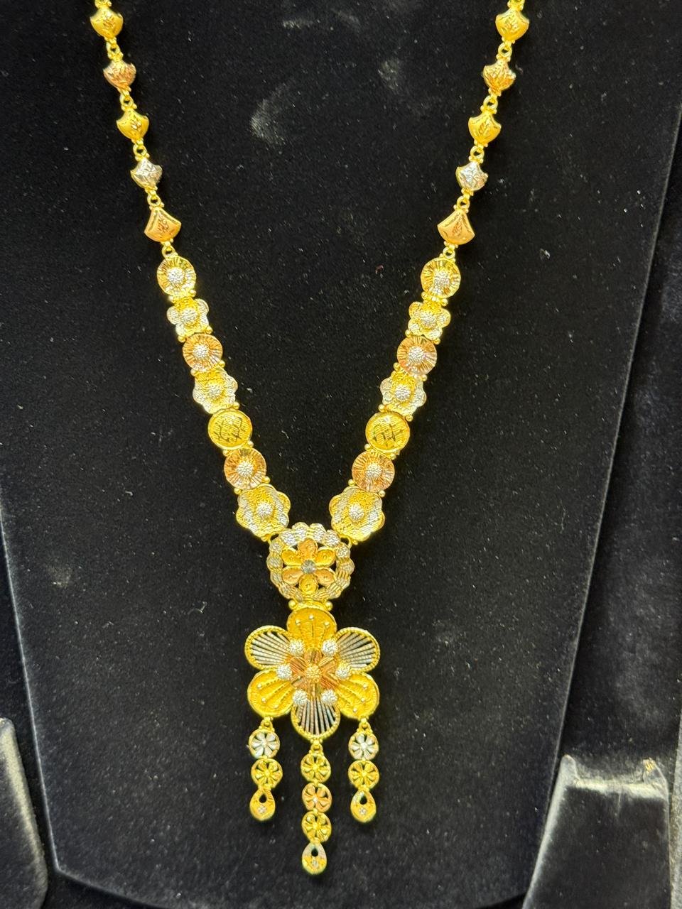 A tri-tone gold necklace with a floral pendant, alternate piece