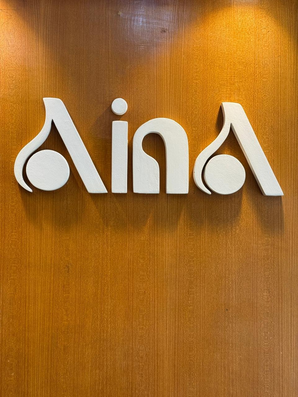 The Aina Gold wordmark sign, mounted on the showroom wall